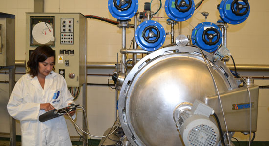 Personal técnico inspeccionando maquinaria de procesado de alimentos en una fábrica conservera