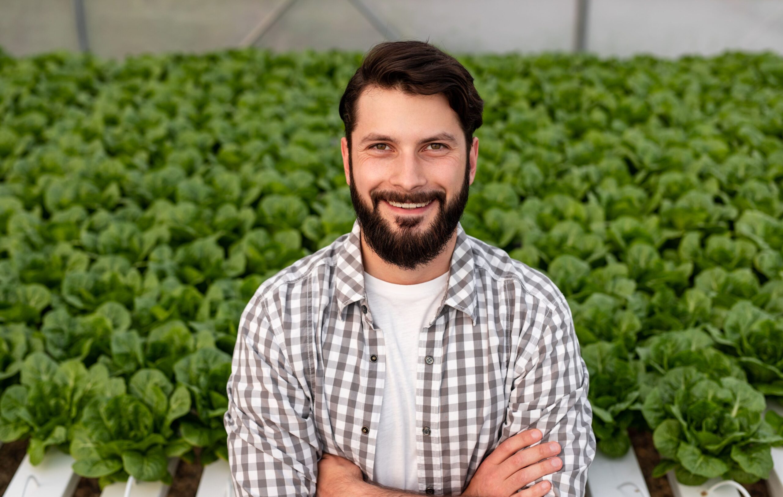 Empresario alegre en invernadero con plantas